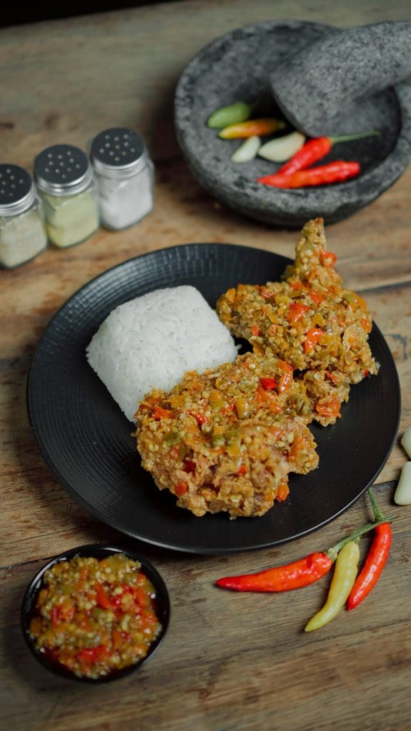 Delicious spicy Indonesian fried chicken served with rice, highlighted against a rustic background in Medan.
